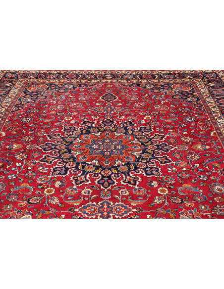 Esplora l'eleganza di questo tappeto Mashad persiano, annodato a mano in lana. Presenta un vivace campo rosso, medaglione centra