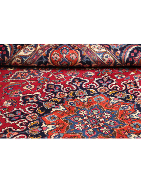 Esplora l'eleganza di questo tappeto Mashad persiano, annodato a mano in lana. Presenta un vivace campo rosso, medaglione centra