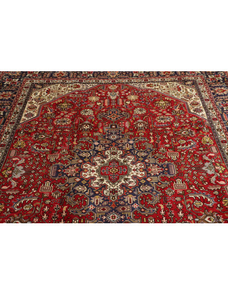 Original Persian Tabriz rug. Central medallion, red field, blue border. Hand-carded wool. Timeless elegance and tradition.