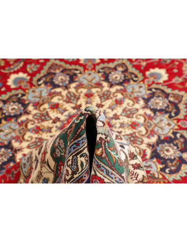 Discover the elegance of a Persian Tabriz rug. Vibrant red field, floral medallion, and dark blue borders. Crafted from hand-car
